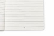 Close-up of a DOT notebook refill page showing ruled lines, page number, and rounded corner