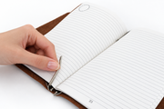 Refill being clipped into the DOT Notebook's silver clips