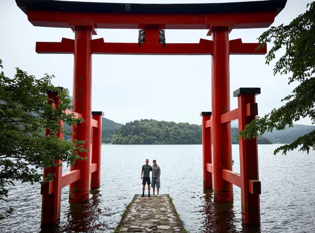 Two people standing under a red torii gate on Lake Ashi in Hakone, Japan
