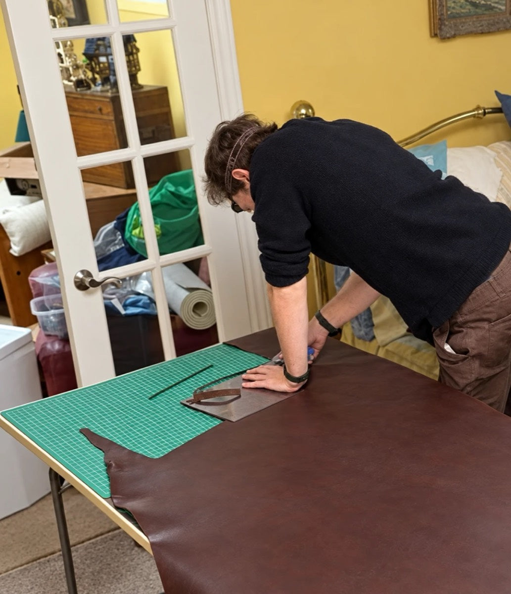 Cutting a DOT cover from a full hide of brown leather on a cutting mat